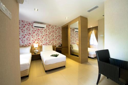 a hotel room with two beds and a mirror at De Palma Resort Kuala Selangor in Kuala Selangor