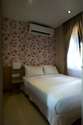 a bedroom with a white bed with a red wall at De Palma Resort Kuala Selangor in Kuala Selangor