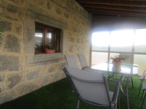a table and chairs in a room with a stone wall at Holiday Home La Asomailla in Hoyos del Espino