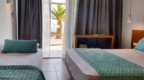 a hotel room with two beds and a window at Mougre studios in Polychrono