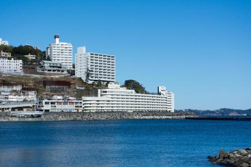 a large white building next to a body of water at Wisterian Life Club Atami in Atami