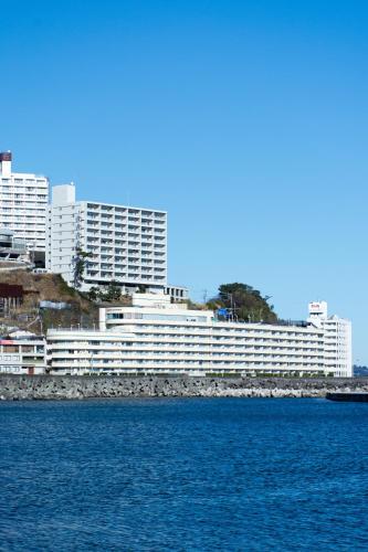 a large white building next to a body of water at Wisterian Life Club Atami in Atami