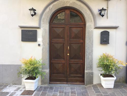 een houten deur op een gebouw met twee potplanten bij 108 b&b in Grotte di Castro