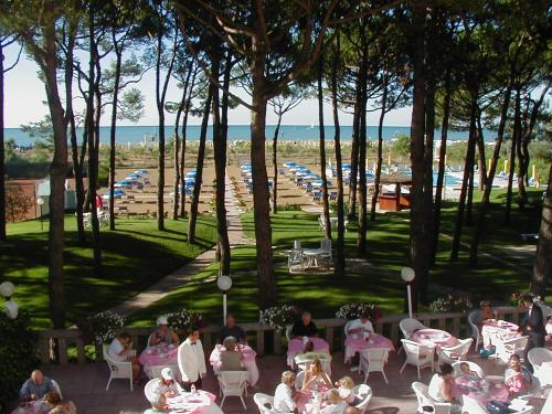 Un groupe de personnes assises à des tables dans un parc dans l'établissement Hotel Beau Rivage Pineta, à Lido di Jesolo