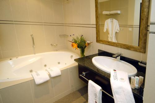 a bathroom with a tub and a sink and a mirror at Sunbird Mount Soche in Blantyre