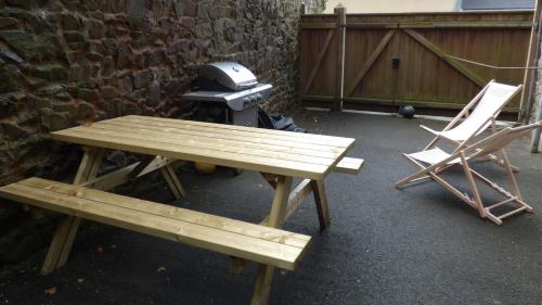 a picnic table and a grill and a chair at La Maison du Palus in Plouha