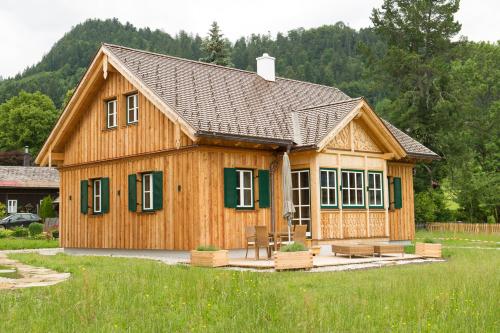 a wooden house with green shutters on a field at Chalet Altaussee in Altaussee