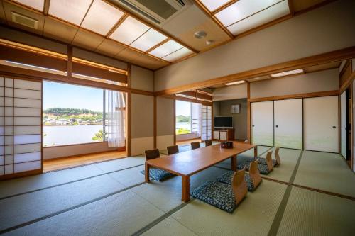 a large room with a table and chairs and windows at Awara Kitagata Onsen Kohanso Hana Yurari in Awara