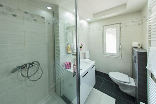 a white bathroom with a shower and a toilet at Apartments Travel in Otočac