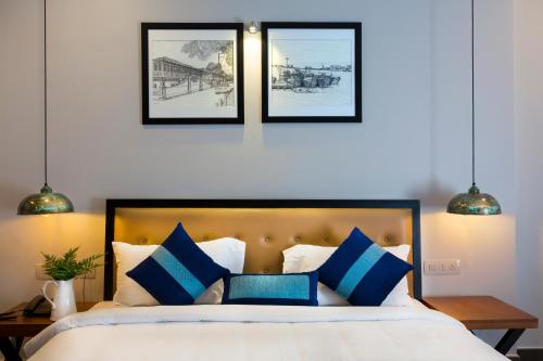 a bedroom with a bed with blue and white pillows at Hotel Neighbourhood, Cochin in Cochin