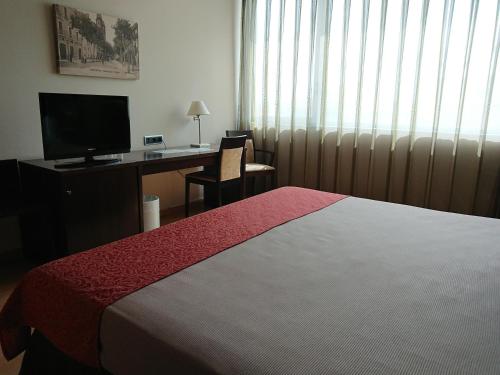 a hotel room with a bed and a desk at Tarraco Park Tarragona in Tarragona