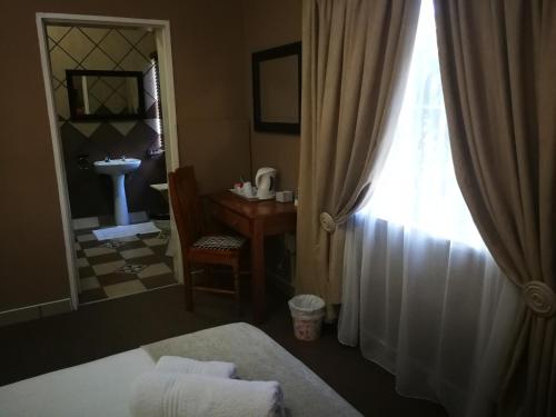 a room with a bed and a window and a desk at Augrabies Falls Lodge & Camp in Augrabies