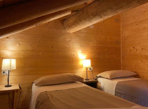 2 camas en una habitación con paredes de madera en Ca dal Cros, en Campertogno