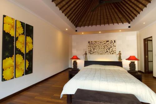 a bedroom with a large bed and two lamps at Ellora Villa in Sanur