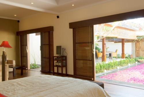 a bedroom with a bed and a large window at Ellora Villa in Sanur