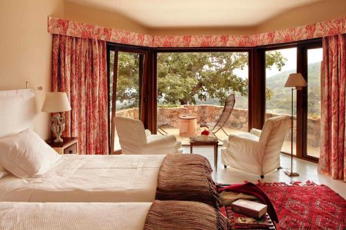 a bedroom with a bed and chairs and a large window at Hotel Nabia in Candeleda