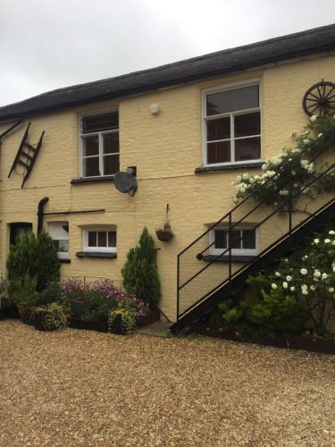 una casa amarilla con una escalera delante de ella en The Coach House at The Bull Inn en Milton Keynes