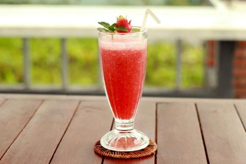 a drink in a glass sitting on a wooden table at The Garuda Villa and Restaurant in Bedugul