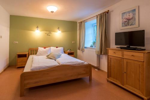 a bedroom with a bed with a flat screen tv at Ferienwohnungen Hotel Garni Dörflerwirt in Aflenz Kurort