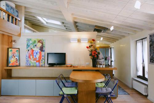 Una habitación con una mesa y sillas y un televisor. en Attico dell'Artista, en Desenzano del Garda