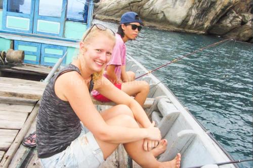 two people sitting in a boat with a fishing pole at Nhi Lo Home Stay in Tân Hiệp