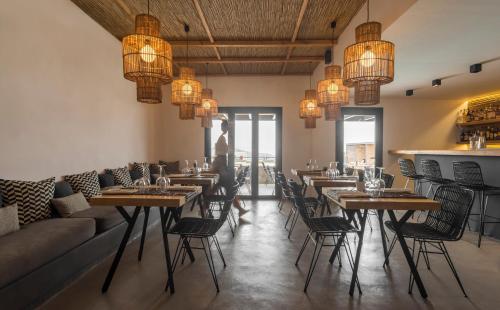 un restaurante con mesas, sillas y lámparas de araña en My Mykonos Hotel, en Mykonos ciudad