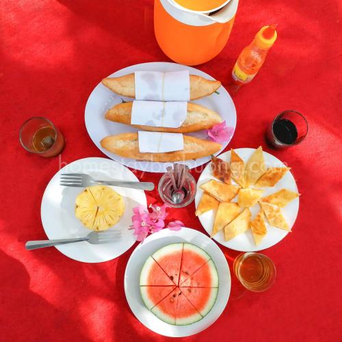 a table with plates of food on a red table at Nhi Lo Home Stay in Tân Hiệp