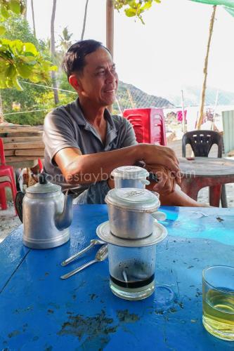 a man sitting at a table with a blue table at Nhi Lo Home Stay in Tân Hiệp