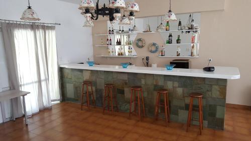 a kitchen with a bar with four stools at Aratos Hotel in Parikia