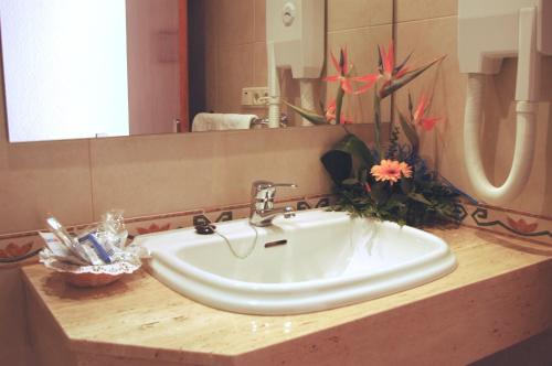 a bathroom sink with a mirror and flowers in it at Hotel Masa International in Torrevieja
