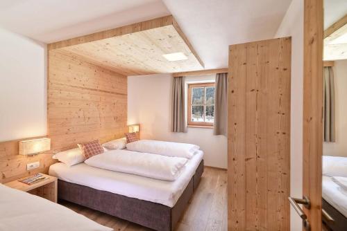 um quarto com 2 camas num quarto com paredes de madeira em Schäfer Apartments em Sesto