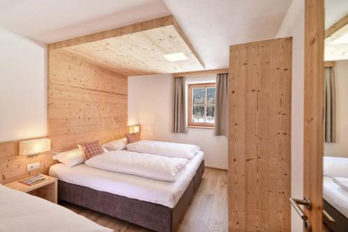 a bedroom with two beds in a room with wooden walls at Sch&auml;fer Apartments in Sesto