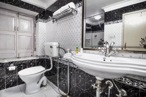 W łazience znajduje się umywalka, toaleta i lustro. w obiekcie Hotel Sugan Niwas Palace w mieście Dżajpur