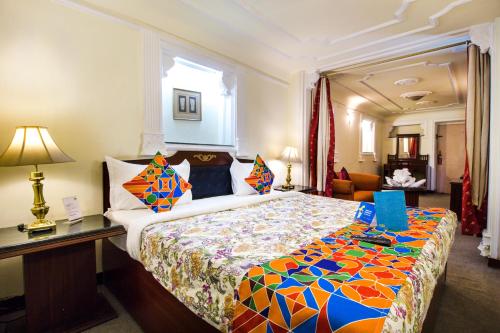 um quarto com uma cama grande e uma colcha colorida em Hotel Sugan Niwas Palace em Jaipur