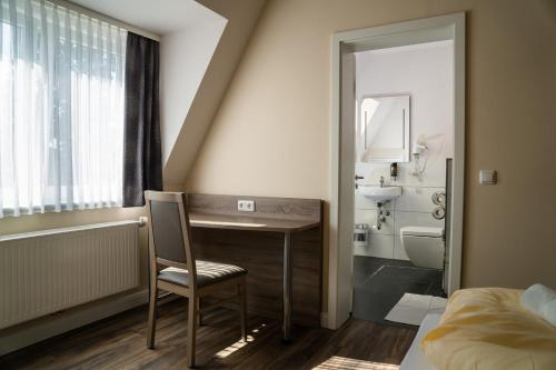 a bathroom with a desk and a sink and a toilet at Hotel Dea in Soltau