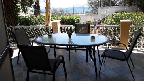 a glass table and chairs on a patio at Βlueview in Ermioni