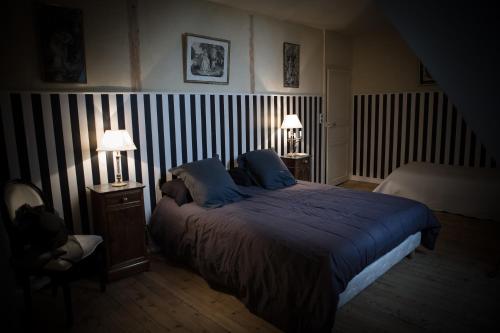 a bedroom with a large bed with blue sheets and two lamps at Chateau De La Moriniere in Beaupréau