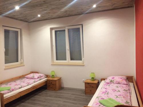 two beds in a room with two windows at Liget in Balatonföldvár