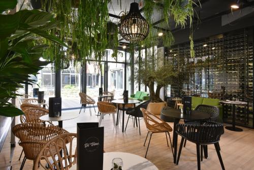 a restaurant with tables and chairs and plants at Martin's All Suites in Louvain-la-Neuve