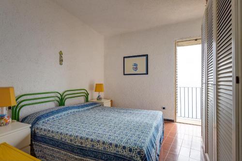 a bedroom with a bed with a blue bedspread and a window at Terrazza Marina in Porto Santo Stefano