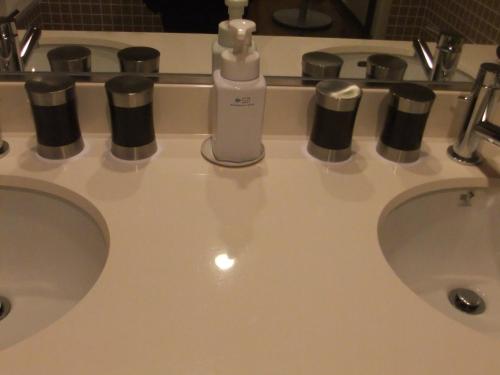 a bathroom sink with two sinks with a bottle of soap at Sutton Hotel Hakata City in Fukuoka