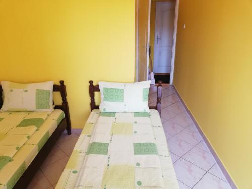 two beds in a room with yellow walls at Smeštaj - sobe MARVEL in Niš