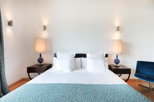 カニャメルにあるVilla Amber by Cap Vermell Estateのベッドルーム1室(ベッド1台、ランプ2つ、青い椅子付)