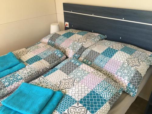 a bed with a quilt and pillows on it at Mobile Homes Comfort ELBA Zelena Laguna in Poreč