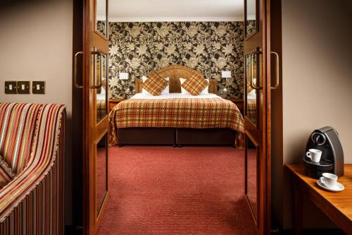a bedroom with a bed and a red carpet at Mercure Maidstone Great Danes Hotel in Maidstone