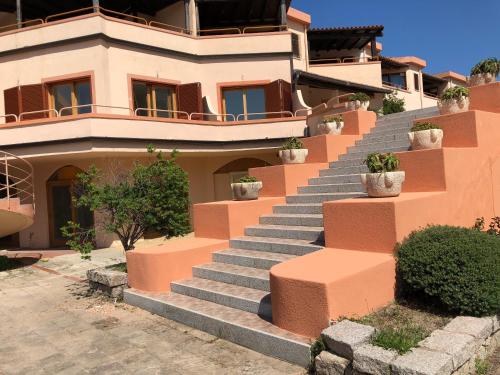 a house with stairs in front of it with potted plants at Case sul mare in Palau