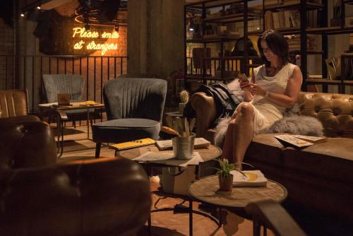 a woman sitting on a couch looking at her cell phone at Upstairs Hotel in Ostend