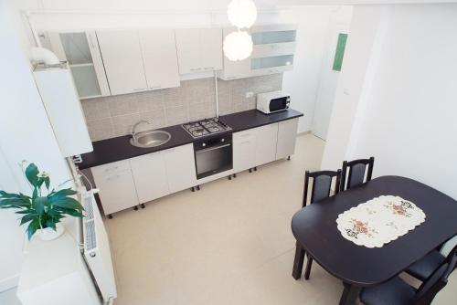 uma cozinha com armários brancos e uma mesa e cadeiras em SunShine Apartment em Brasov