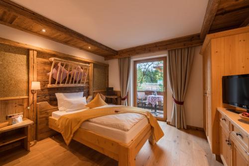 a bedroom with a bed and a tv and a window at Gröbl-Alm in Mittenwald