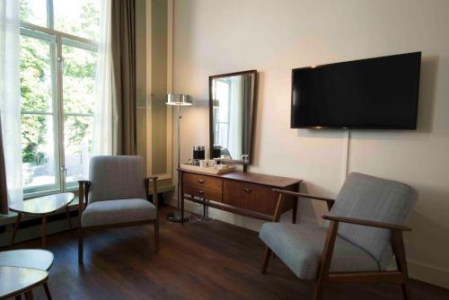 a hotel room with a television and a desk and chairs at Logement 't Oude Bierhuys in Middelburg
